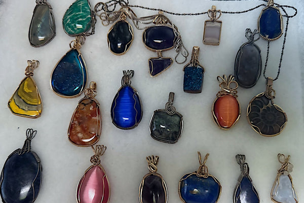 Collection of various colorful gemstone pendants on a white background